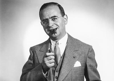 Max Steiner in a suit smoking a cigar.