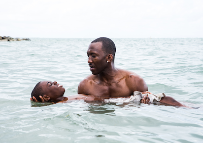 A man holding a young boy afloat in the ocean.