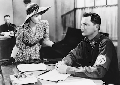 A woman talking to a man wearing a swastika.