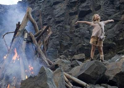 A girl spreading her arms near a fire.