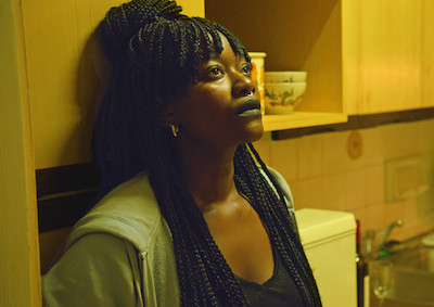 A woman leaning against a cabinet in a kitchen.
