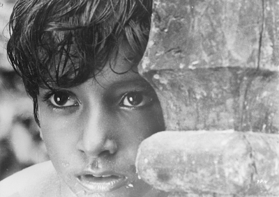 A young boy looking out from behind a wall.