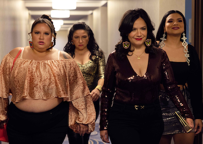 Four women walking down a hotel hallway.