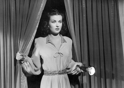 Joan Bennett holding a flashlight.