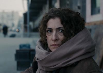 A woman wearing a large scarf and standing outside.
