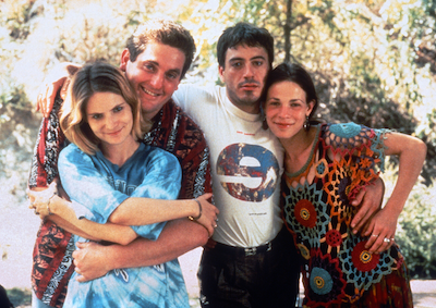 Four people smiling and standing with their arms wrapped around each other.