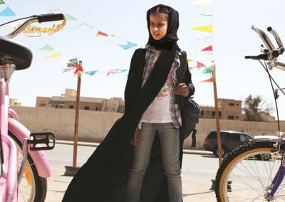 A young girl with a backpack next to bicycles.