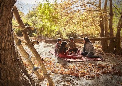 Four kids sitting in a circle outside.