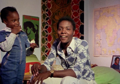 A woman sitting in a bedroom with a young child.