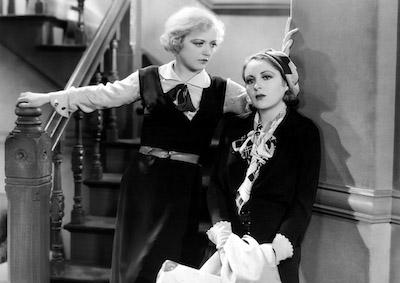 Two women standing at the foot of some stairs.