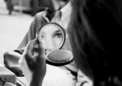 A woman looking into a compact mirror. 
