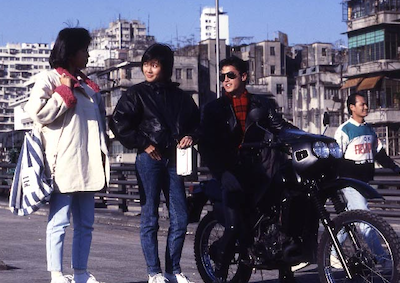Three people talking in a city street.