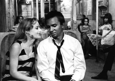A woman smiling at a man on a subway car.