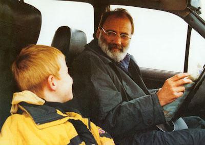 A man and a boy smiling in a car.