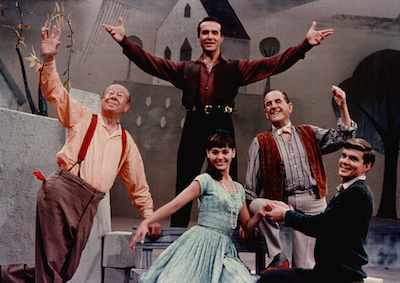 Five actors posing on a theater stage.