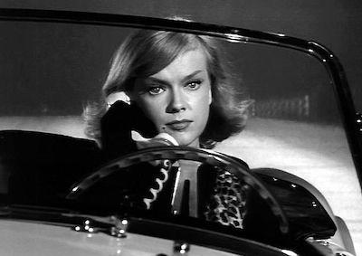 Anne Francis driving and holding a phone.