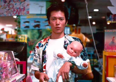 A man holding a plastic baby in a store.
