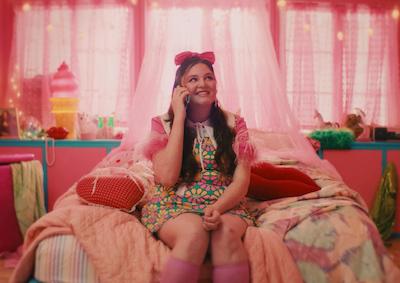 A person smiling on a bed and holding a phone.