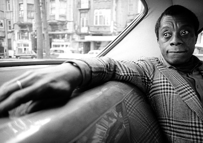 James Baldwin sitting in the back seat of a car.