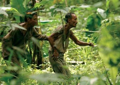 Two men wading through a jungle. 