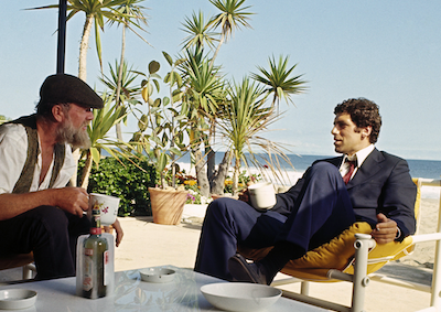 Elliott Gould sitting in a beach chair.