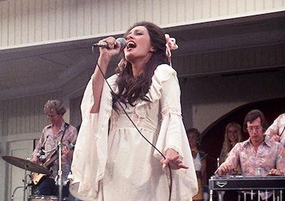 A woman singing on stage with a band.