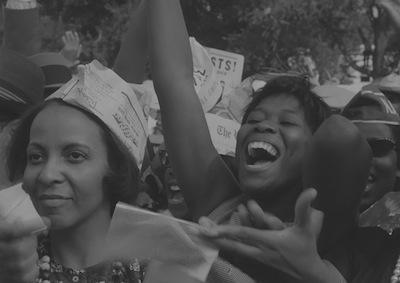 People in a crowd smiling and clapping.