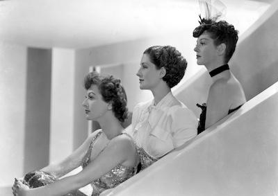 Joan Crawford, Norma Shearer and Rosalind Russell sitting in profile.