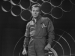 William Shatner standing in a jumpsuit. 