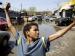 A kid standing with his arms outstretched next to an auto mechanic shop.