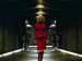 A woman in a red dress walking in front of two figures in armor.