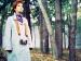 A woman standing among trees with a camera hanging from her neck.