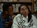 A woman looking away from a man who is talking to her in a library.