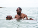 A man holding a young boy afloat in the ocean.