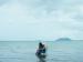 A woman and a girl sitting in a chair in the ocean.