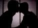 The silhouette of two men kissing.