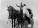 Two people standing in a horse carriage.