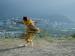 A person dancing on a hill that overlooks a city.